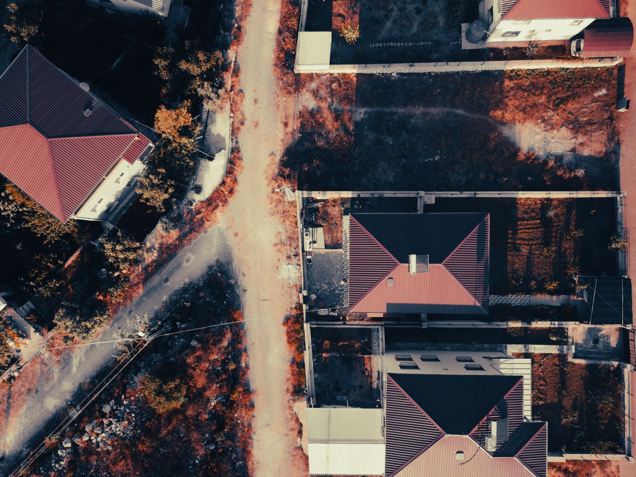 Aerial view showcasing suburban houses with red roofs and adjacent streets.