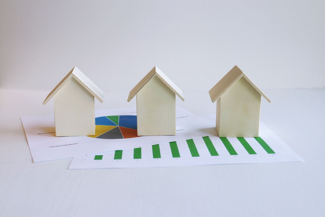 The Art of Drawing Readers In: Your attractive post title goes here Wooden model houses on graphs depict real estate market analysis and trends.