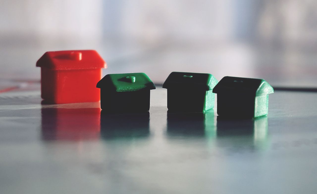 Home Close-up photo of red and green Monopoly game houses on a reflective surface.